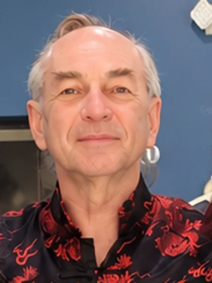 Portrait of Qigong Master Iurii Khomiakov smiling, wearing a black and red dragon-pattern jacket