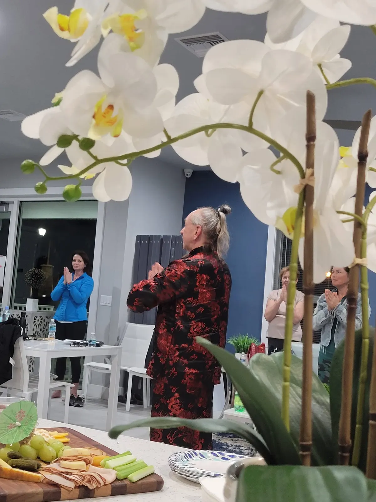 Master Iurii Khomiakov with palms together, leading adult students through a Qigong exercise
